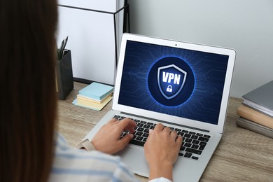 Image of Woman using laptop with switched on VPN at table in office, closeup