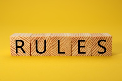 Photo of Word Rules made of wooden cubes with letters on yellow background