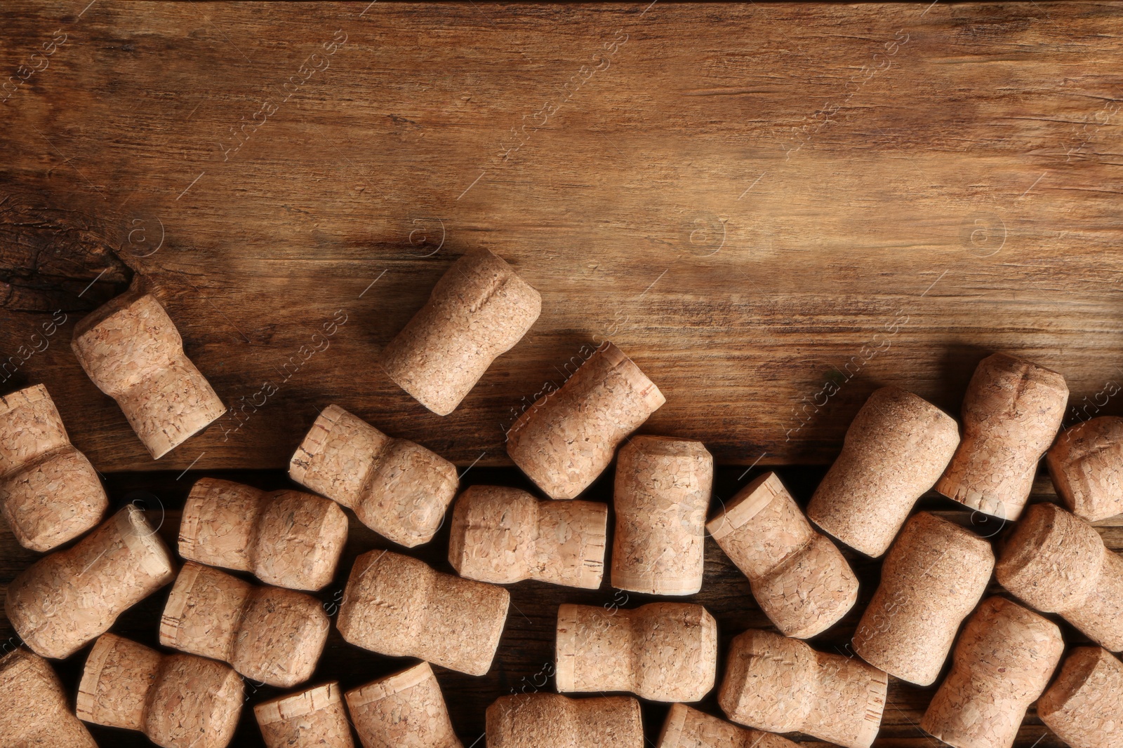 Photo of Sparkling wine bottle corks on wooden table, flat lay. Space for text