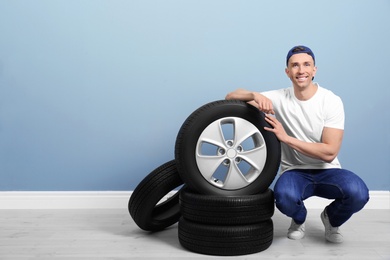 Young man with car tires on color wall background