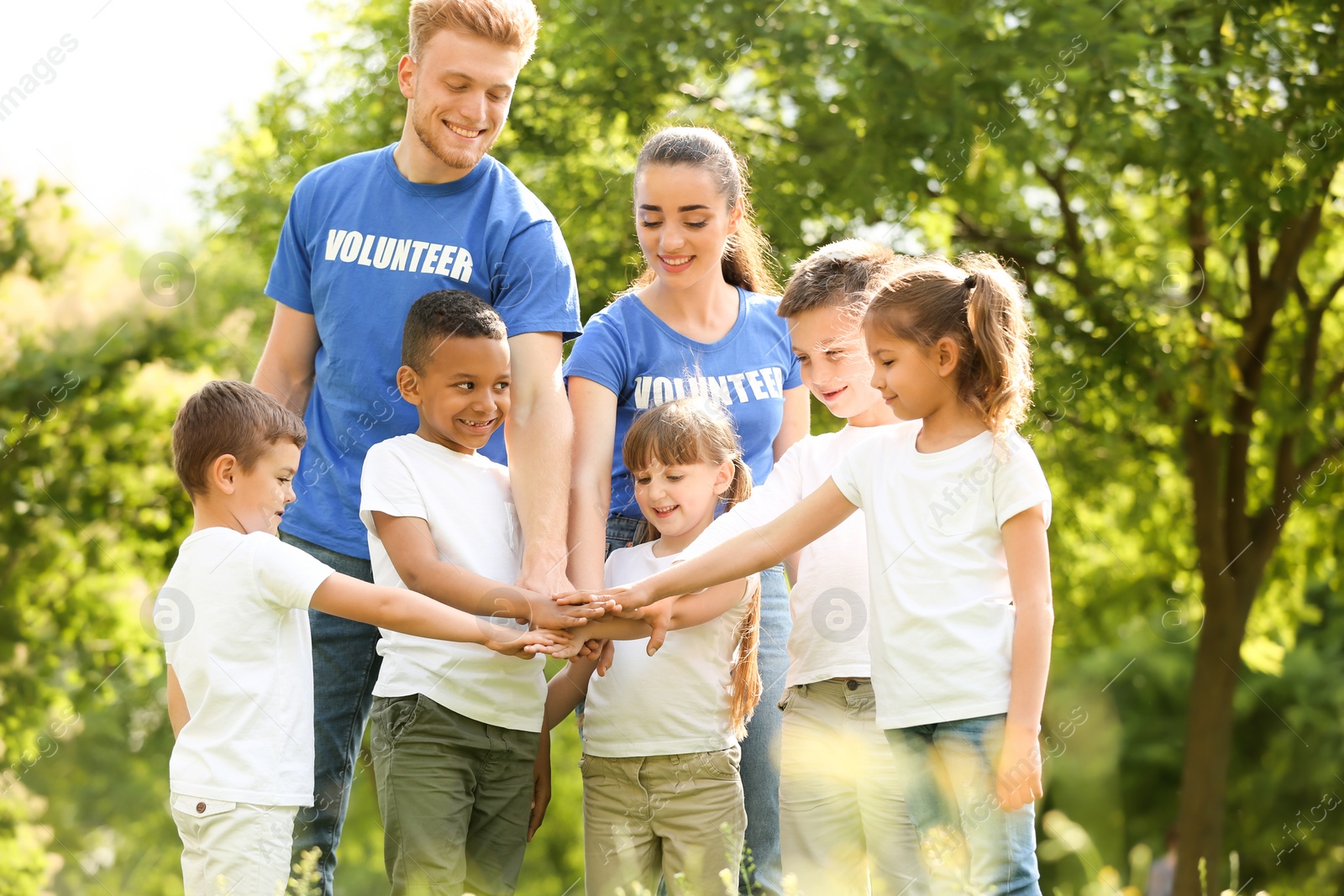 Photo of Group of kids joining hands with volunteers in park