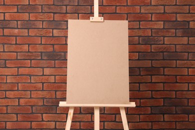 Photo of Wooden easel with blank board near brick wall