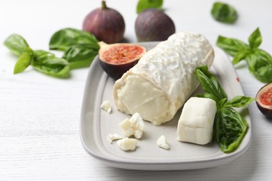 Photo of Delicious goat cheese with basil and figs on white wooden table