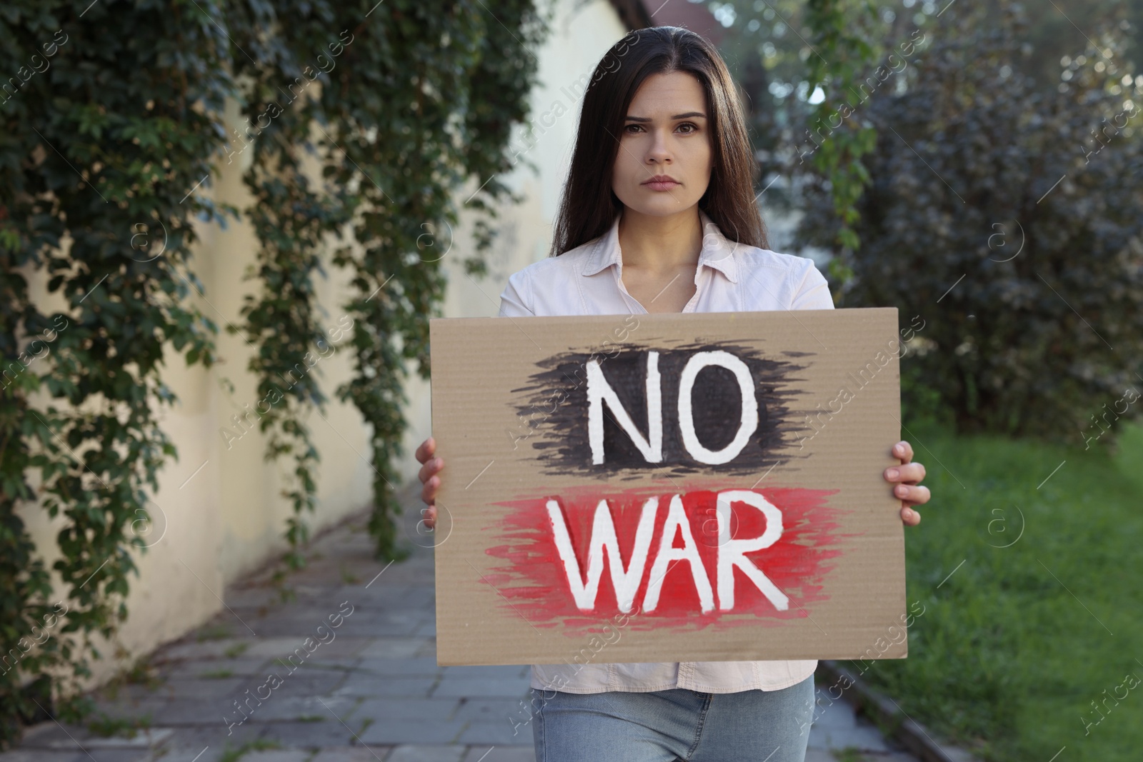 Photo of Sad woman holding poster with words No War outdoors. Space for text