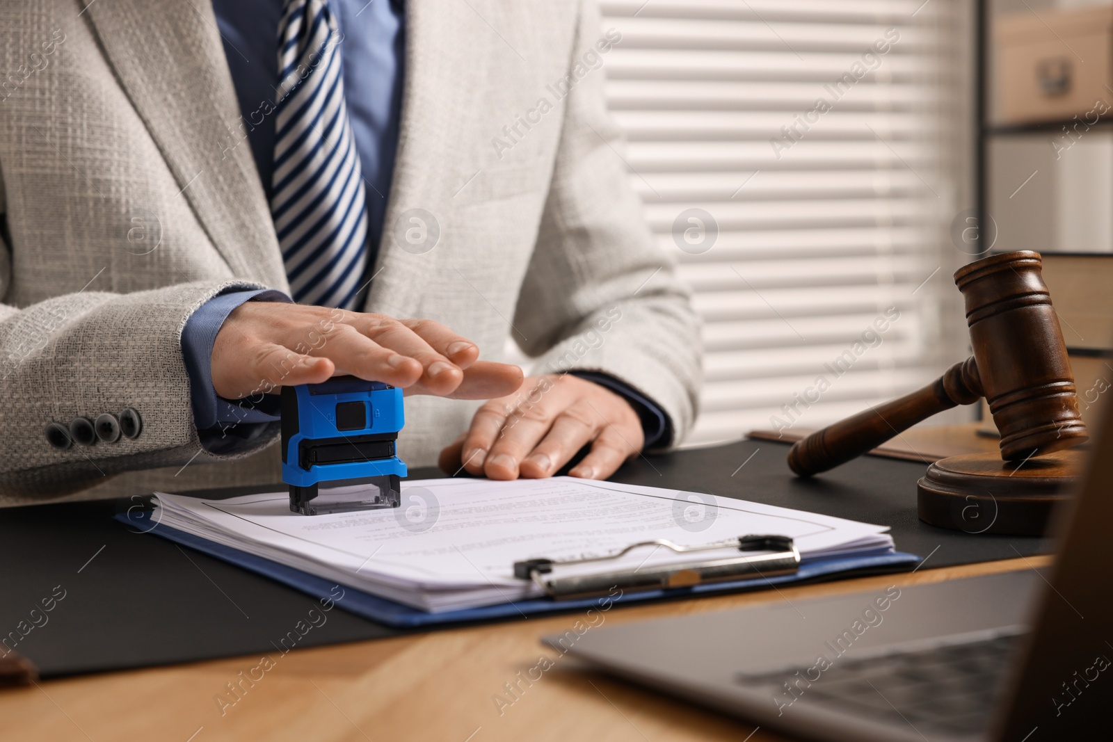 Photo of Notary stamping document at table in office, closeup