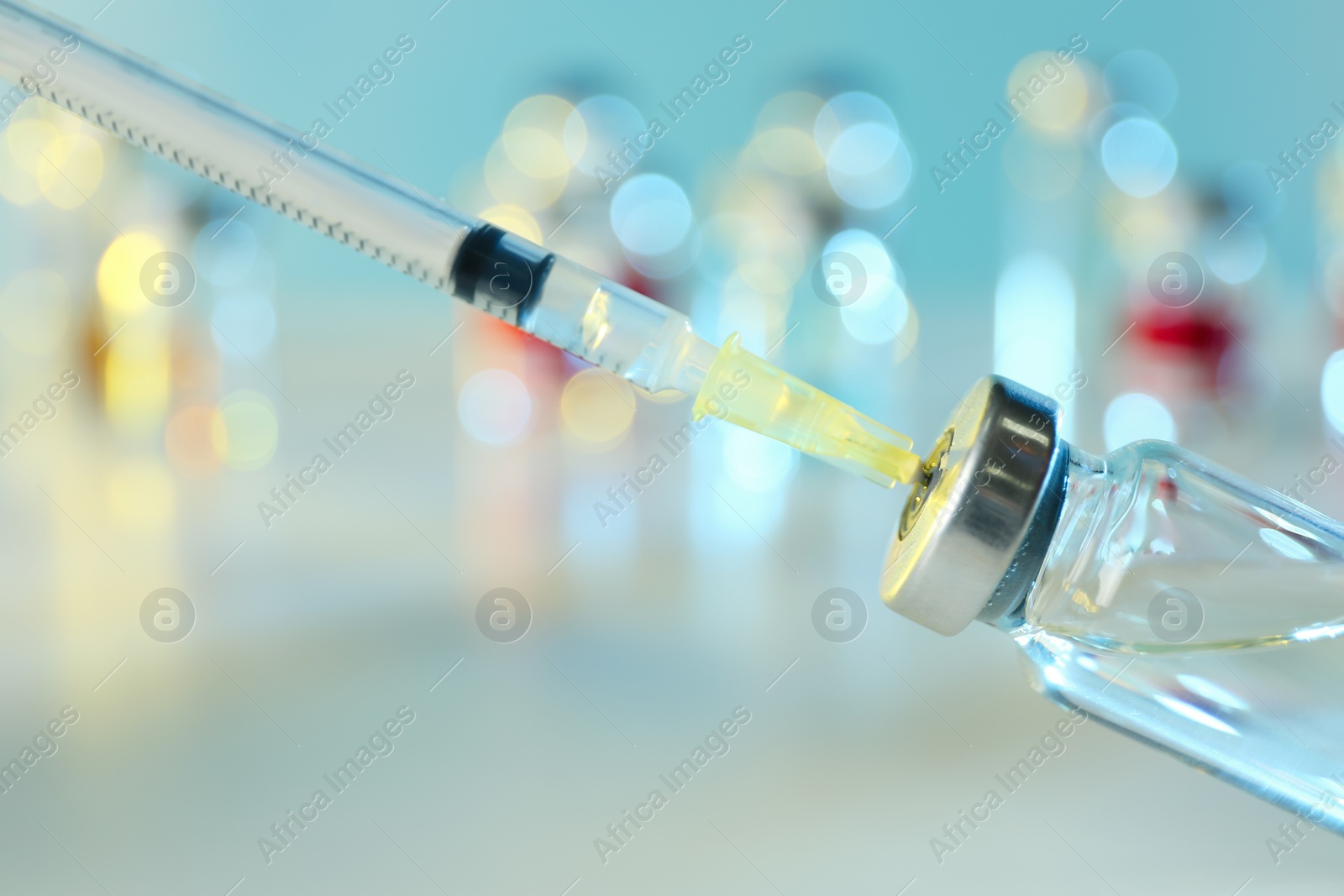 Photo of Filling syringe with medication from vial against blurred background, closeup. Vaccination and immunization