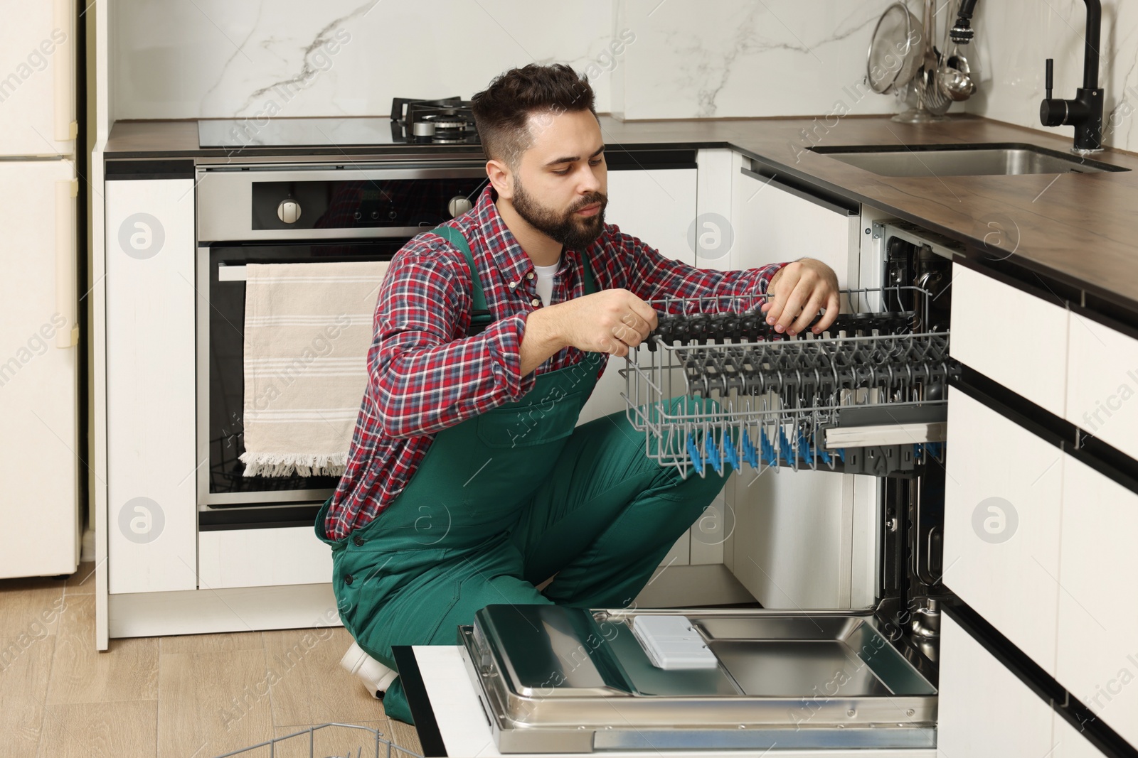 Photo of Serviceman repairing dishwasher cutlery rack in kitchen