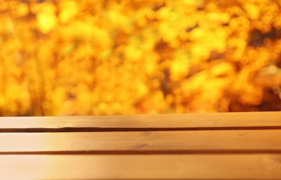 Photo of Wooden table and blurred autumn scenery on background. Space for text