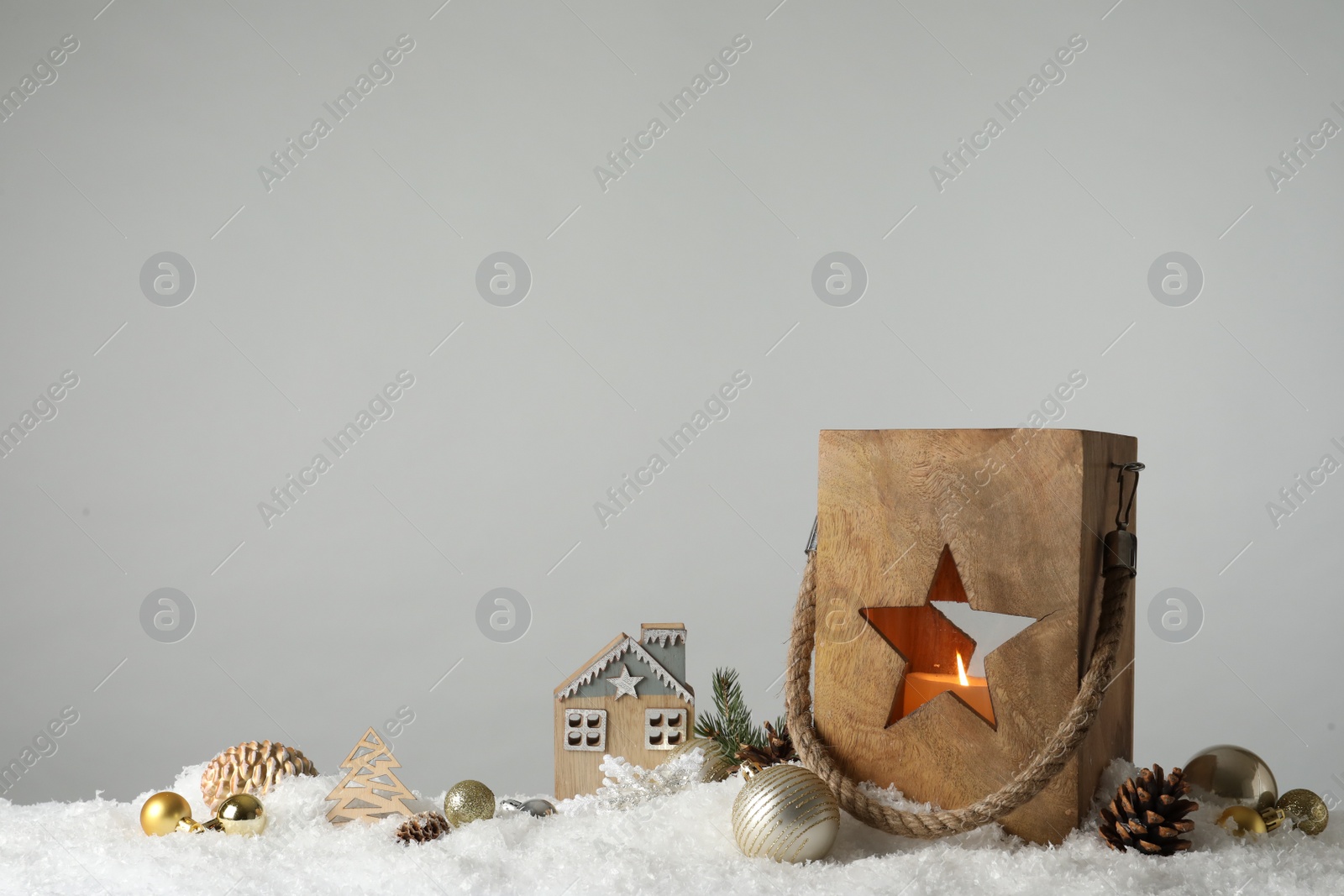 Photo of Composition with wooden Christmas lantern on snow against light grey background, space for text