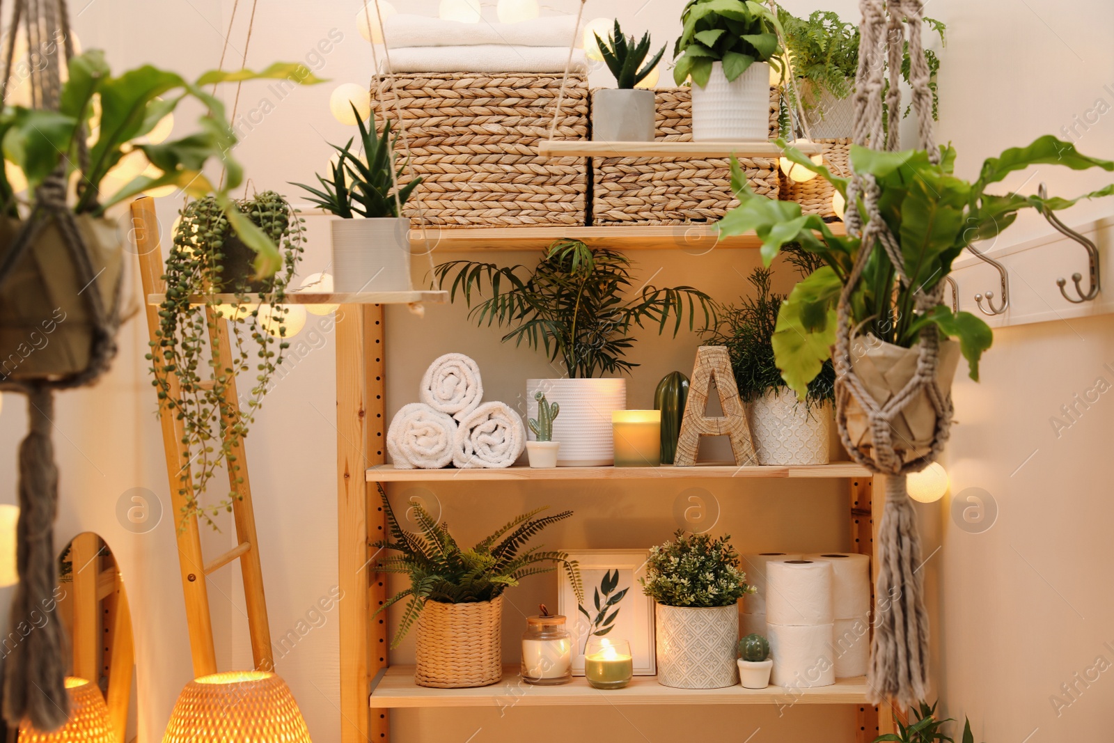 Photo of Wooden shelving unit with green plants and different accessories indoors. Interior design