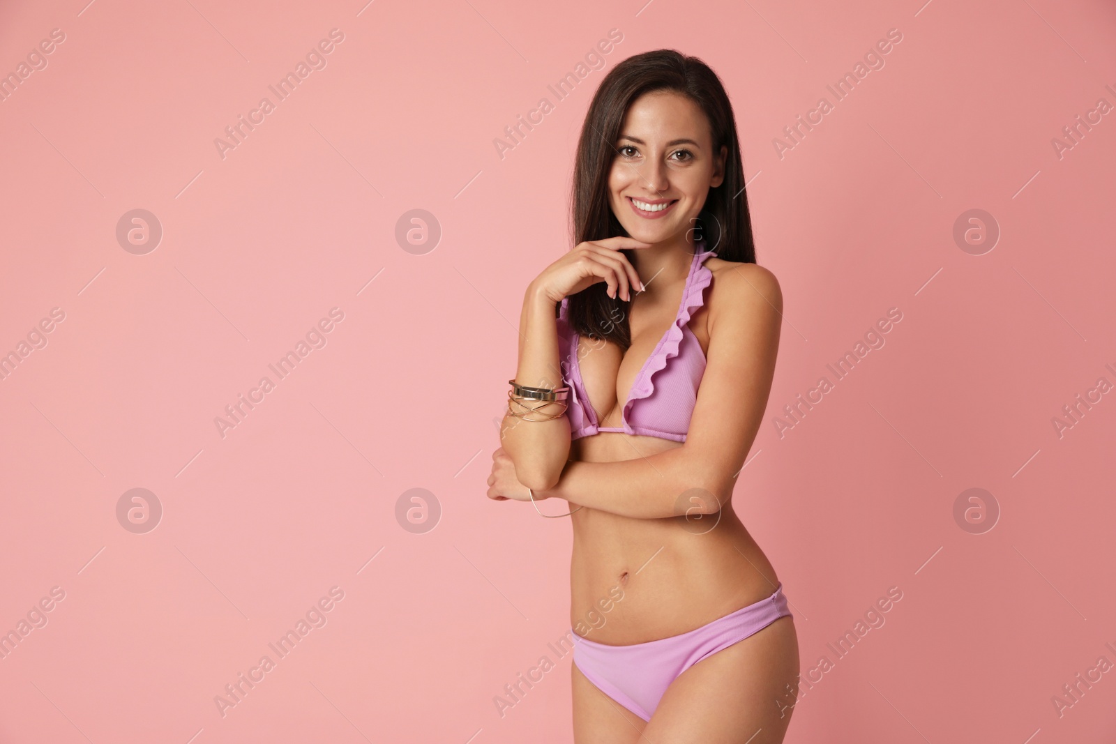 Photo of Pretty sexy woman with slim body in stylish  pink bikini on coral background, space for text