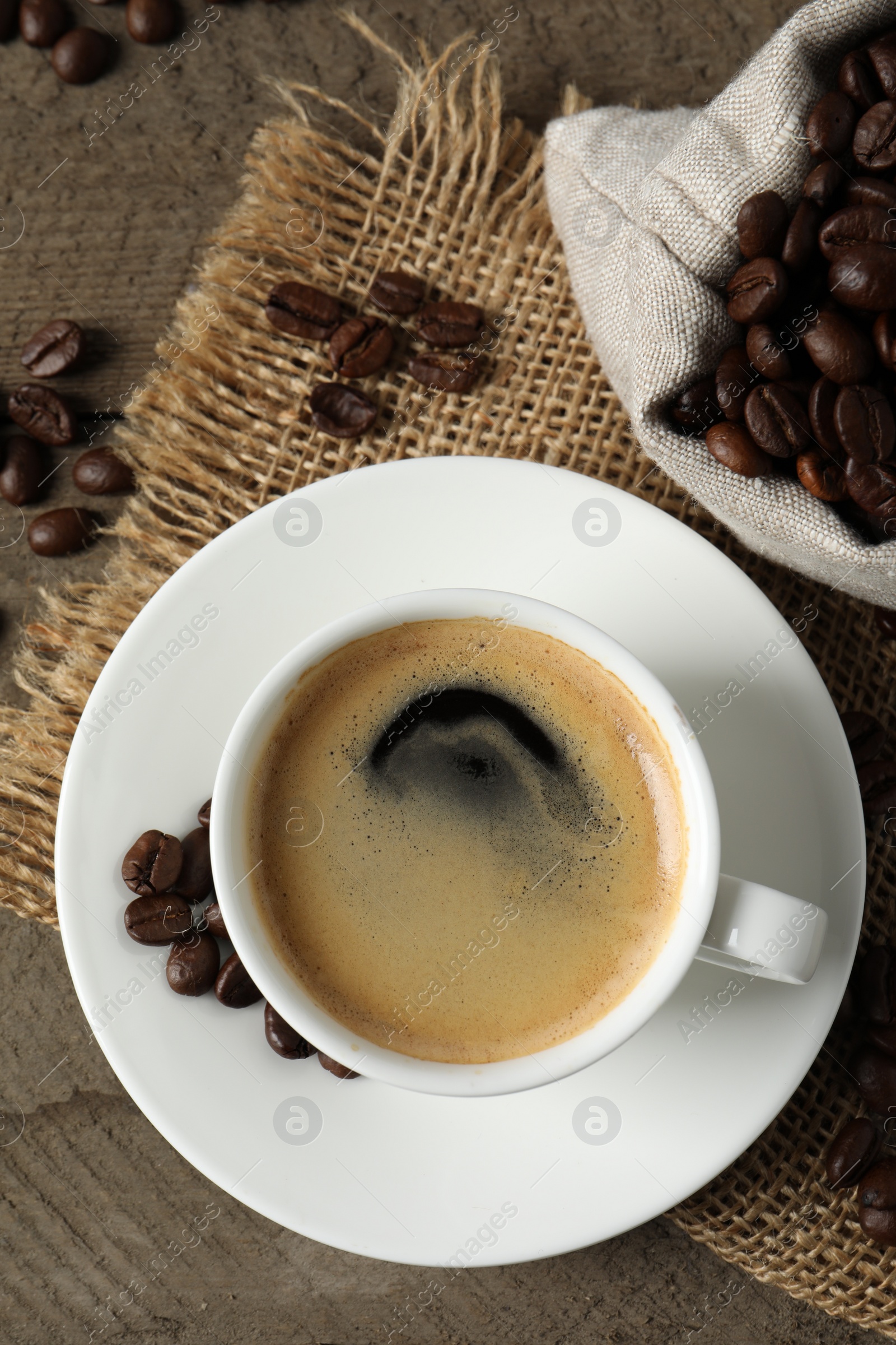 Photo of Cup of aromatic coffee and beans on wooden table, flat lay