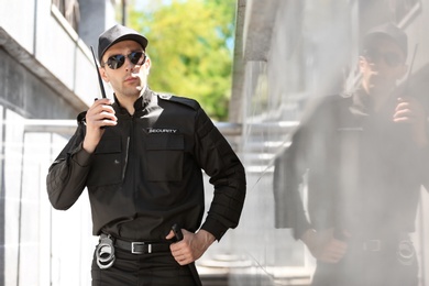 Male security guard using portable radio transmitter outdoors