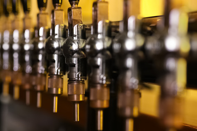 New modern beer taps in pub, closeup. Professional bar equipment