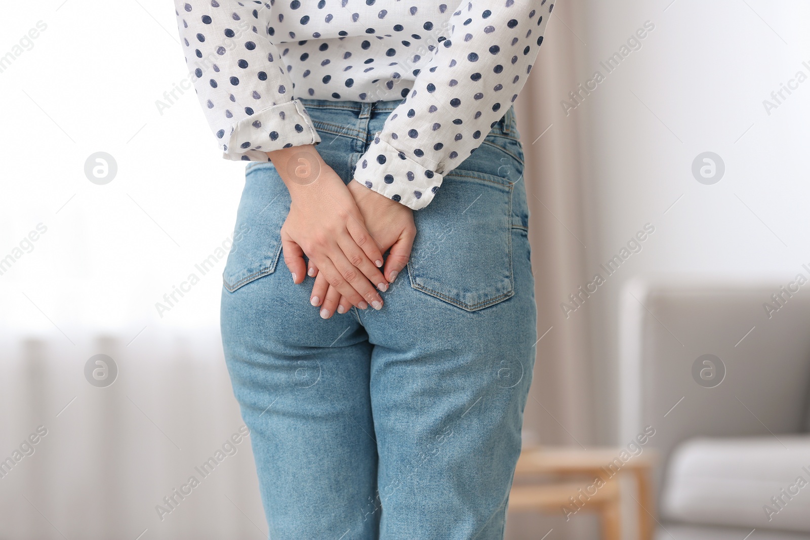 Photo of Young woman suffering from hemorrhoid at home, closeup