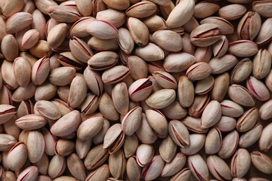 Photo of Many tasty pistachios as background, top view