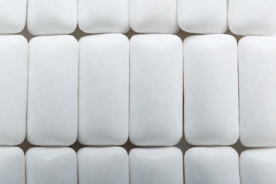 Photo of Tasty white chewing gums as background, top view