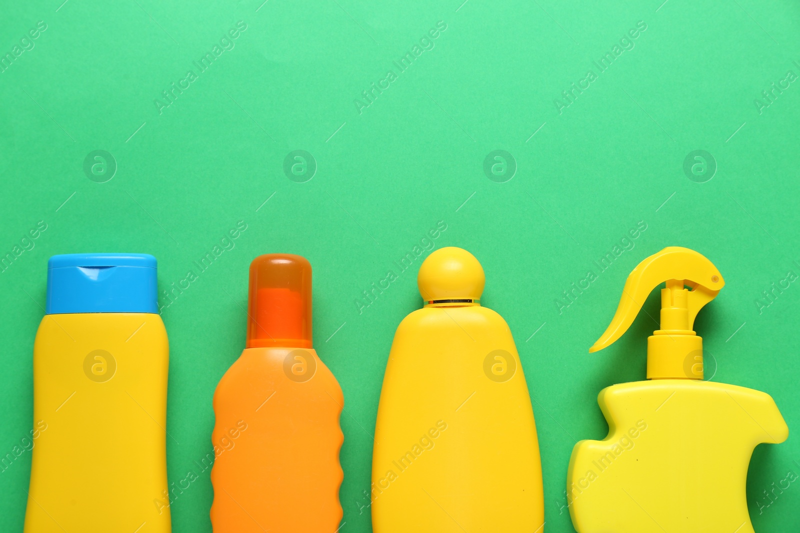Photo of Suntan products on green background, flat lay. Space for text