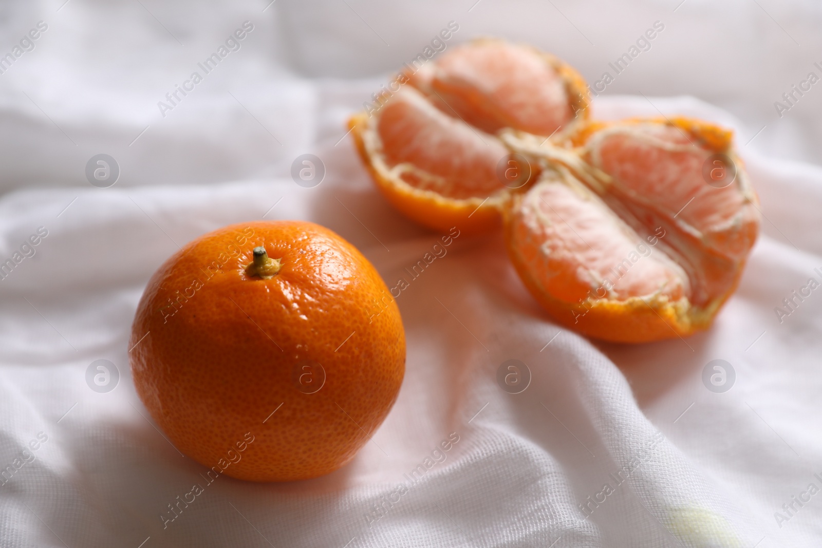 Photo of Fresh ripe tangerines on white cloth, closeup