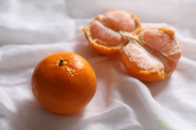 Photo of Fresh ripe tangerines on white cloth, closeup