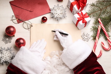 Photo of Santa writing letter at white wooden table, top view