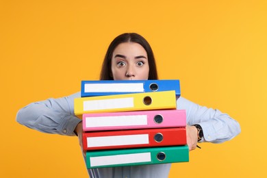 Photo of Shocked woman with folders on orange background