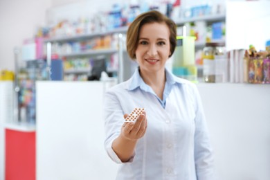 Photo of Professional pharmacist in drugstore, focus on hand with pills