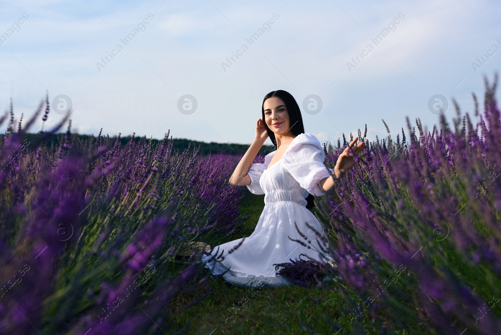 Photo of Beautiful young woman sitting in lavender field