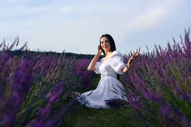 Beautiful young woman sitting in lavender field