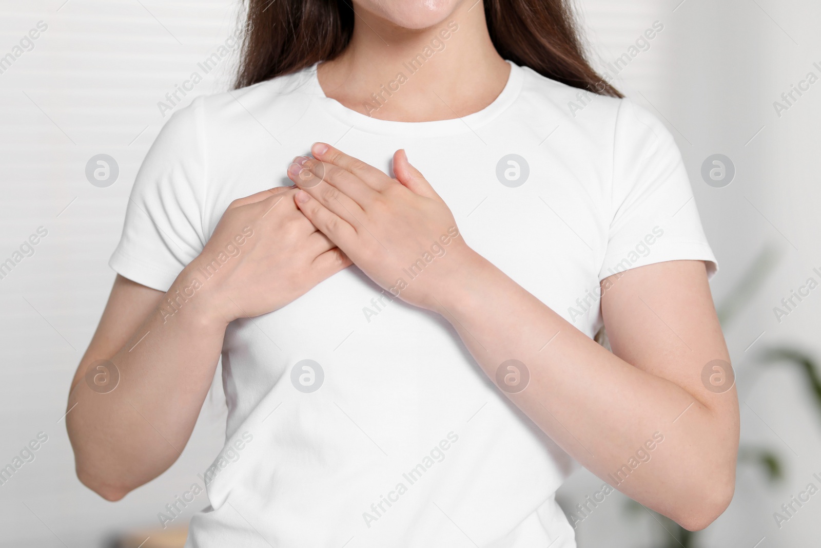 Photo of Thank you gesture. Grateful woman with hands on chest indoors, closeup