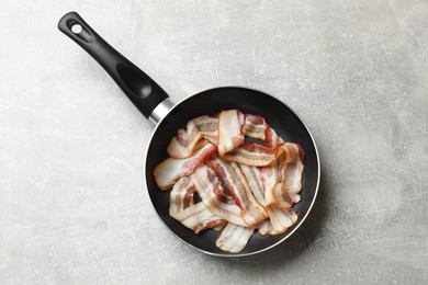 Photo of Delicious bacon slices in frying pan on light grey table, top view