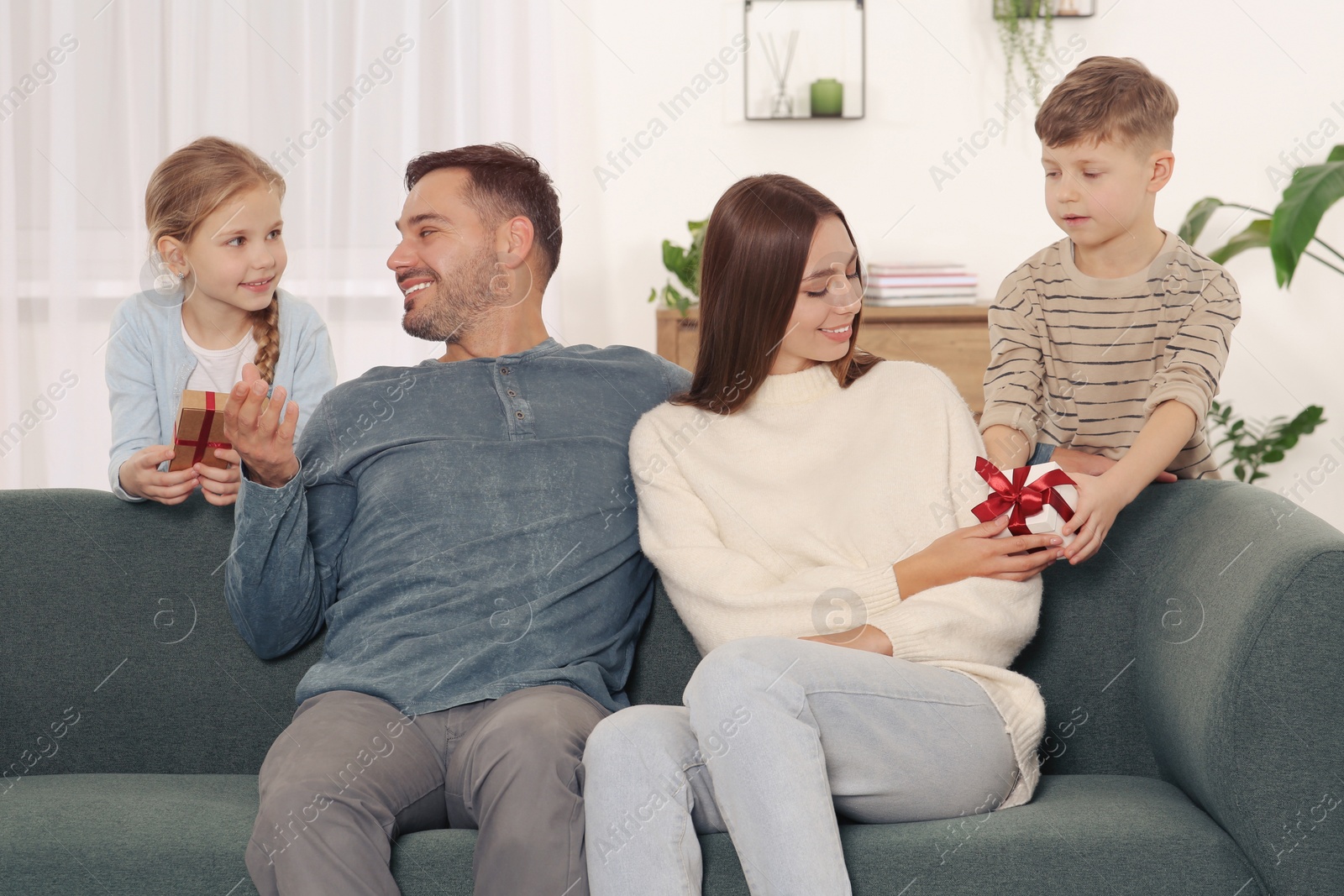 Photo of Little children presenting their parents with gifts at home