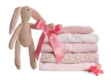 Photo of Stack of baby girl's clothes, pacifier and toy bunny on white background