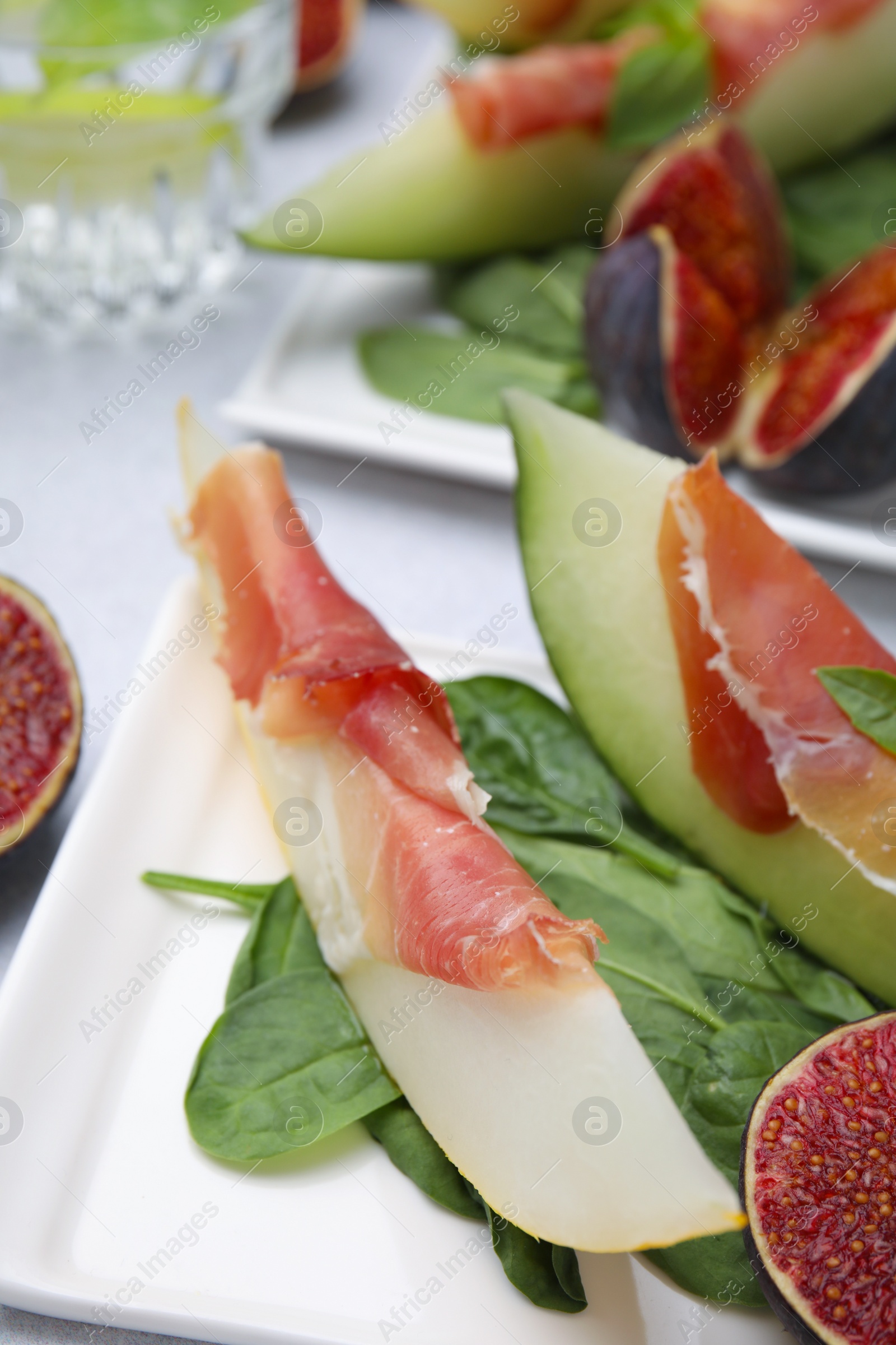 Photo of Tasty melon, jamon and figs served on white plate, closeup