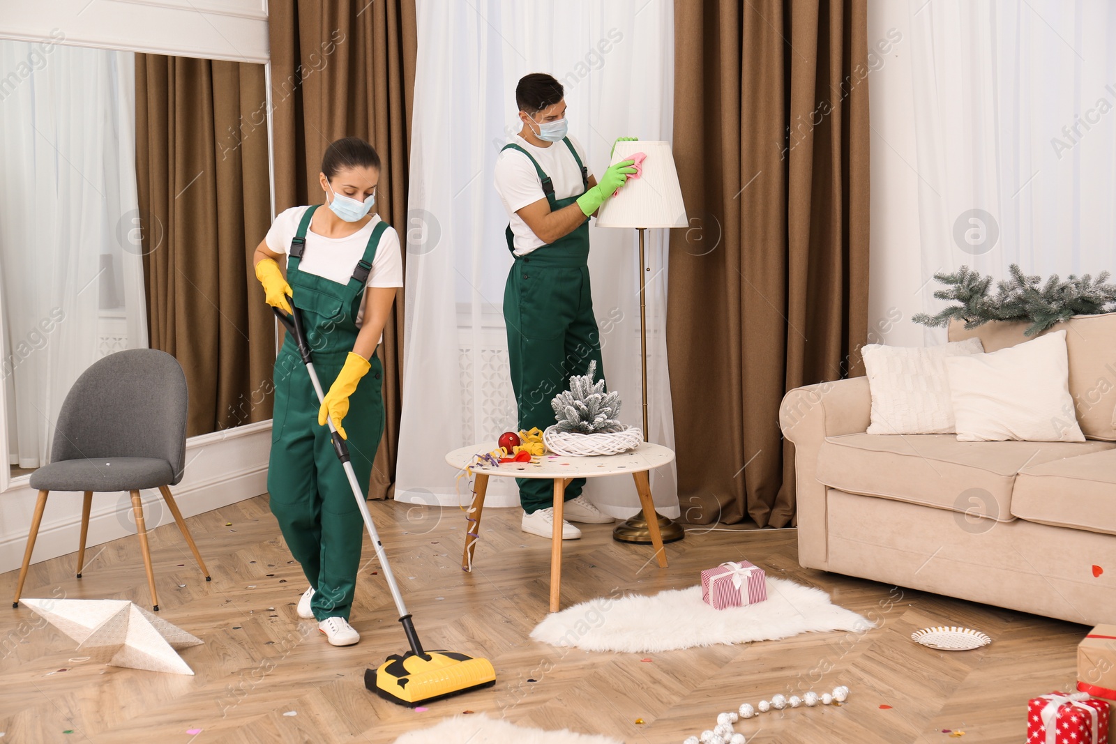 Photo of Cleaning service team working in messy room after New Year party