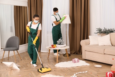 Cleaning service team working in messy room after New Year party