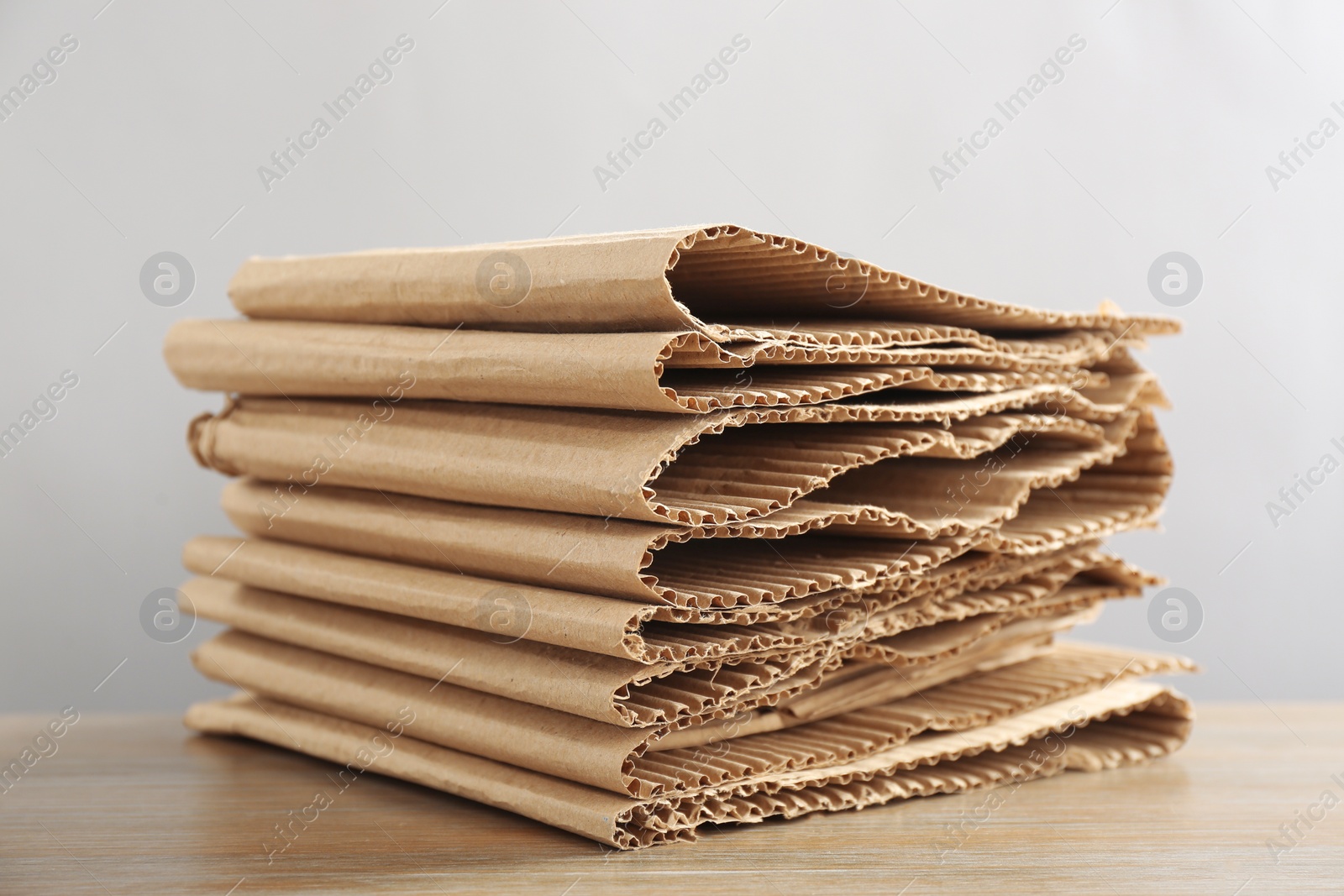 Photo of Stack of cardboard on table against light background, closeup. Recycling concept