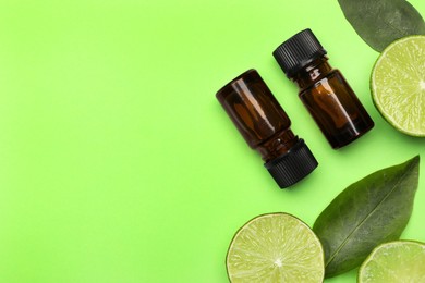 Photo of Bottlescitrus essential oil and fresh limes on green background, flat lay. Space for text