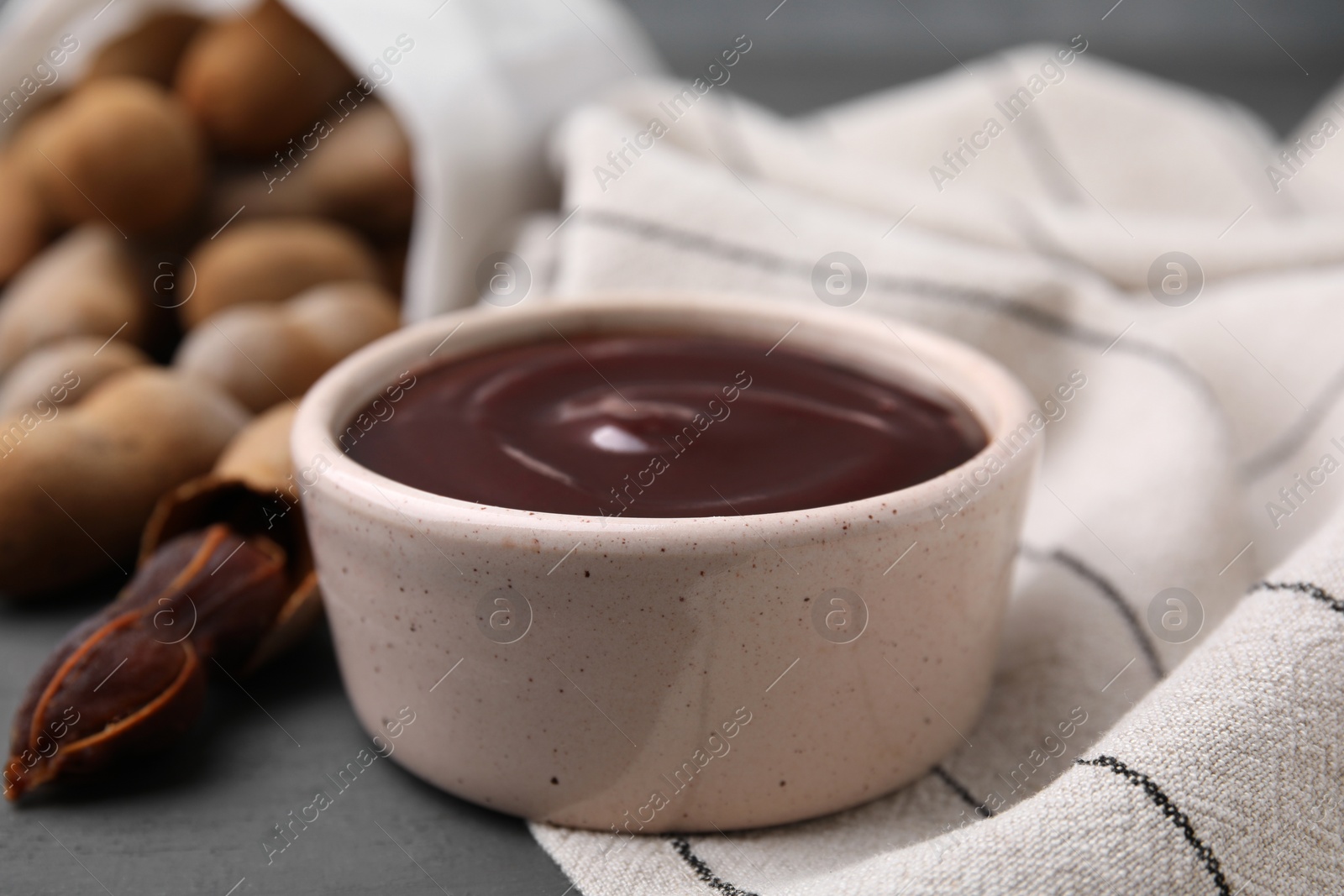 Bowl of tamarind sauce and fresh pods on table, closeup Photo of Bowl of tamarind sauce and fresh pods on table, closeup