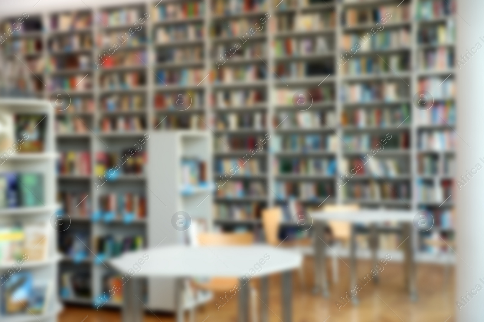 Photo of Blurred view of bookshelves and tables in library