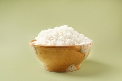 Bowl of tasty cooked rice on color background