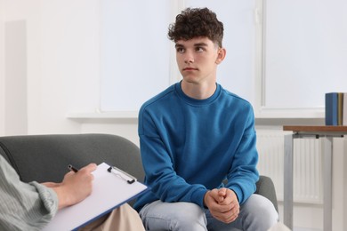 Photo of Psychologist working with teenage boy in office, space for text. Teenager problems