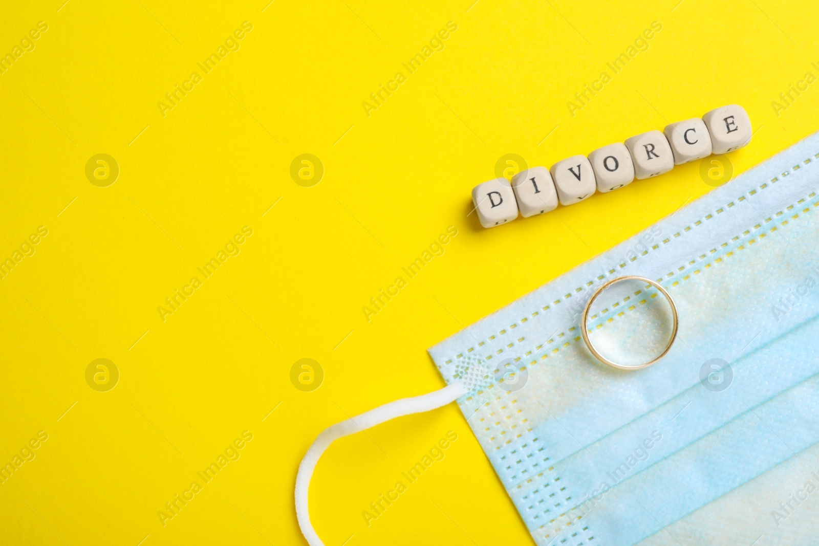 Photo of Flat lay composition with protective mask and wedding ring on yellow background, space for text. Divorce during coronavirus quarantine