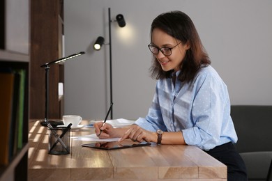 Photo of Woman with modern tablet learning at table indoors