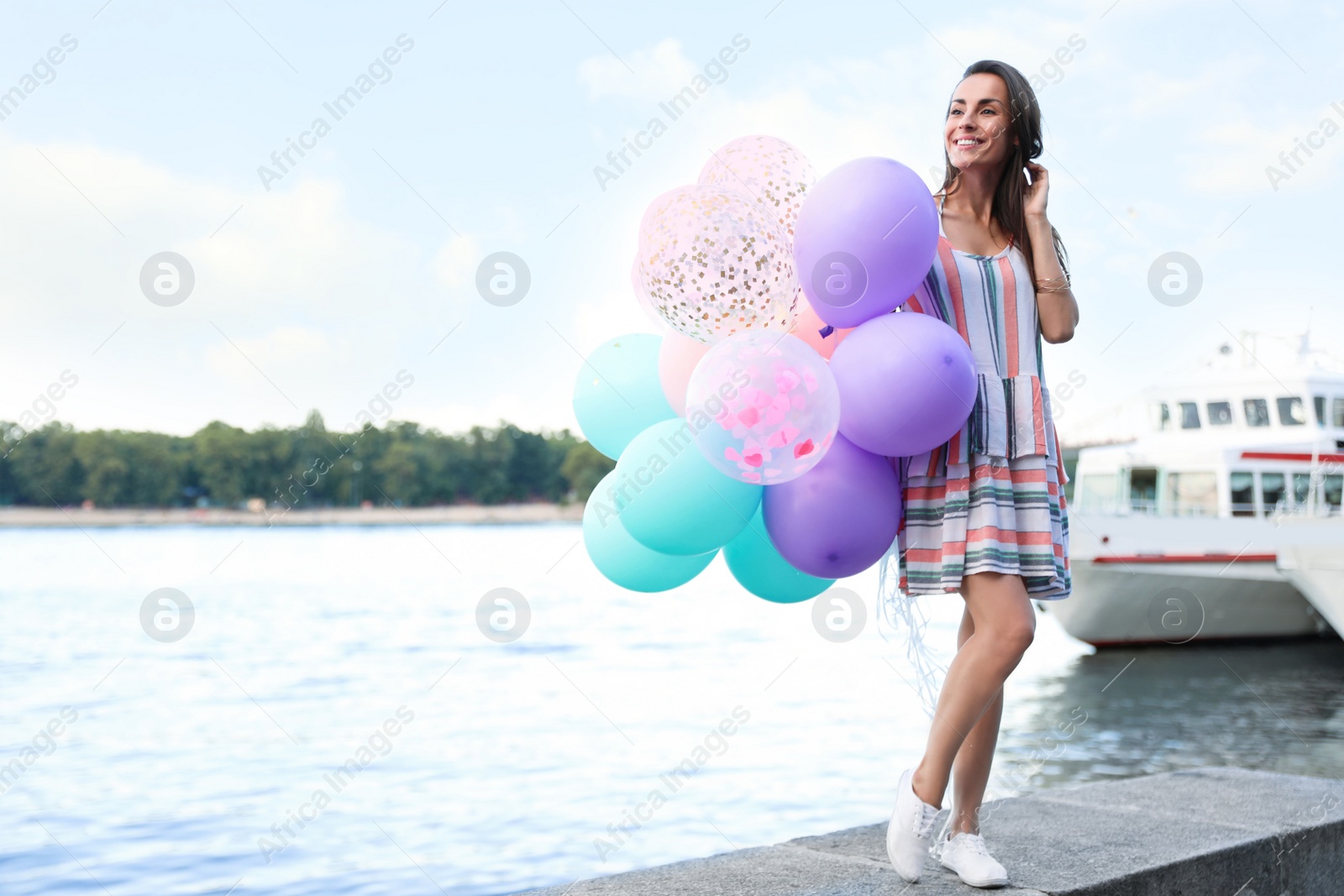 Photo of Pretty young woman with color balloons near river