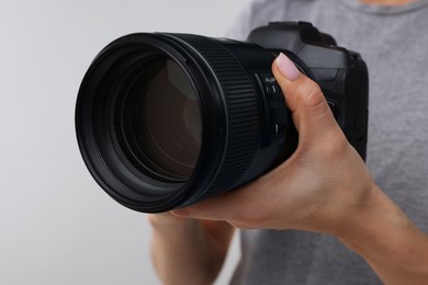 Photo of Photographer with camera on light grey background, closeup