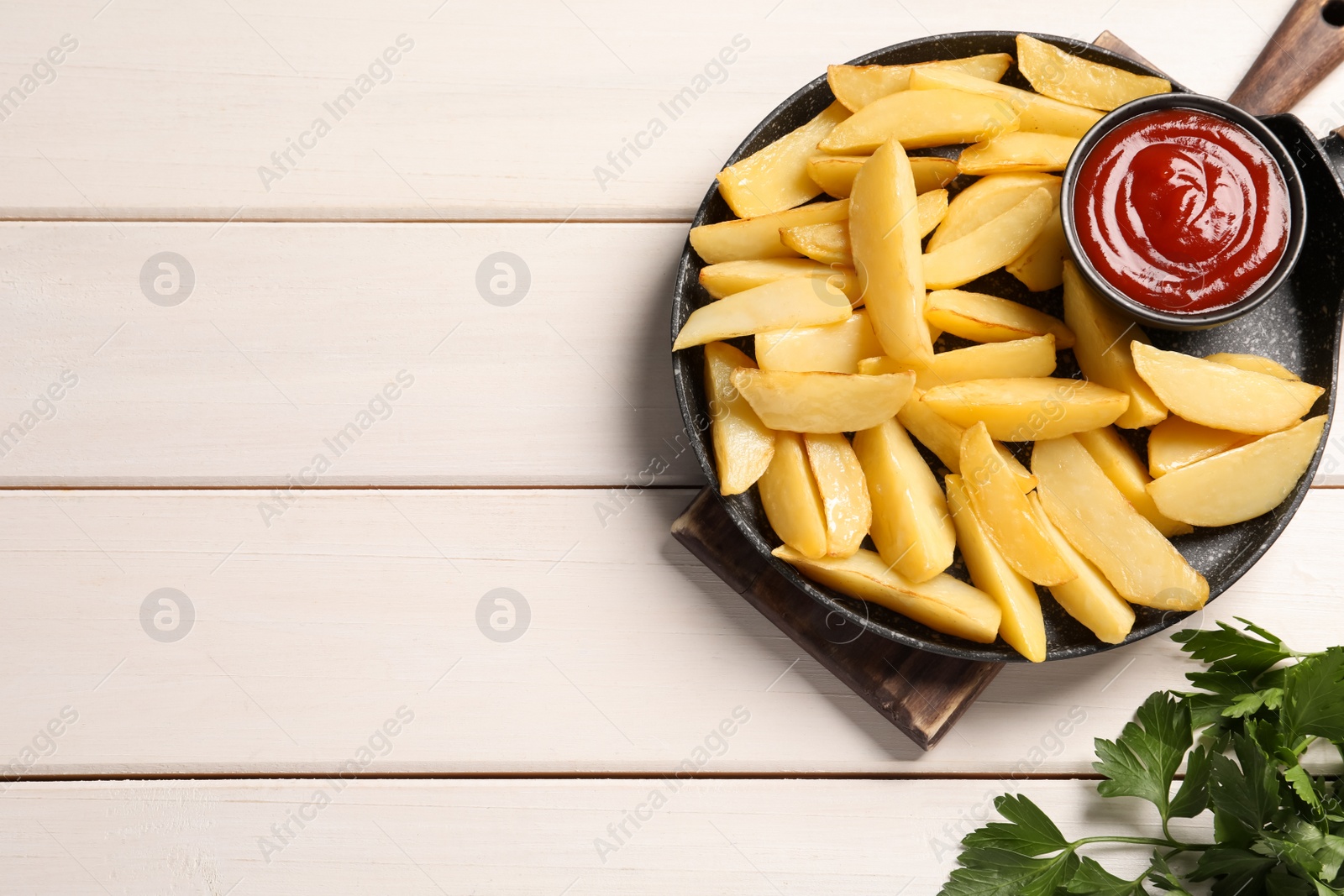 Photo of Pan with tasty baked potato wedges and sauce on white wooden table, flat lay. Space for text