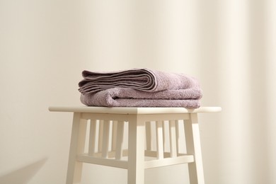 Violet towels on stool against white wall