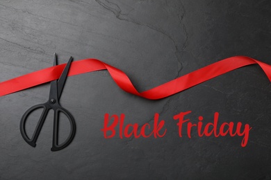 Photo of Phrase Black Friday, ribbon and scissors on dark background, flat lay