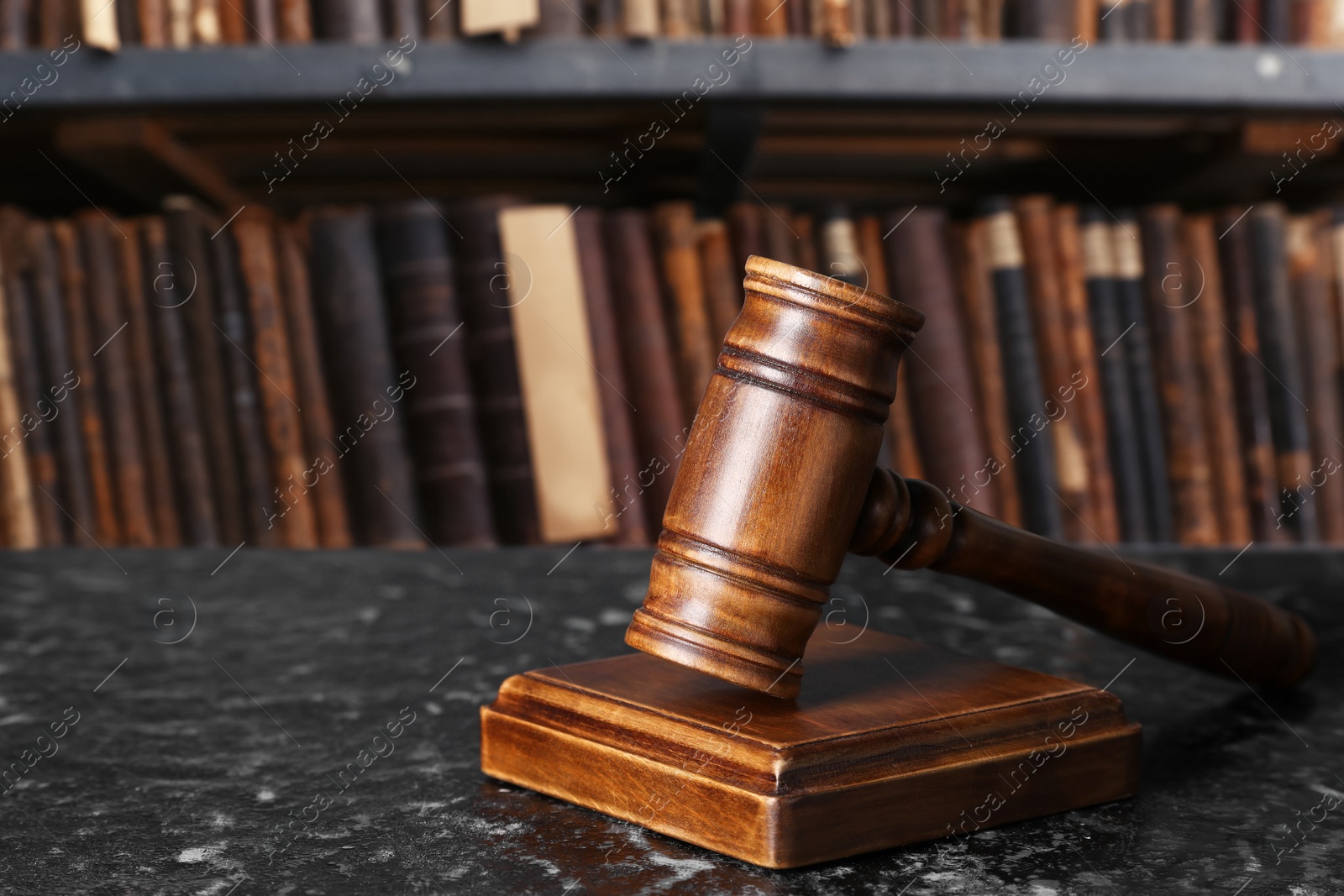 Image of Law. Judge's gavel on dark textured table against shelf with books indoors, space for text